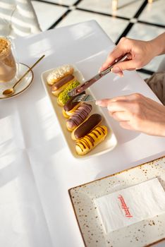 Stylish composition of gourmet eclairs with a latte in a bright cafe setting.