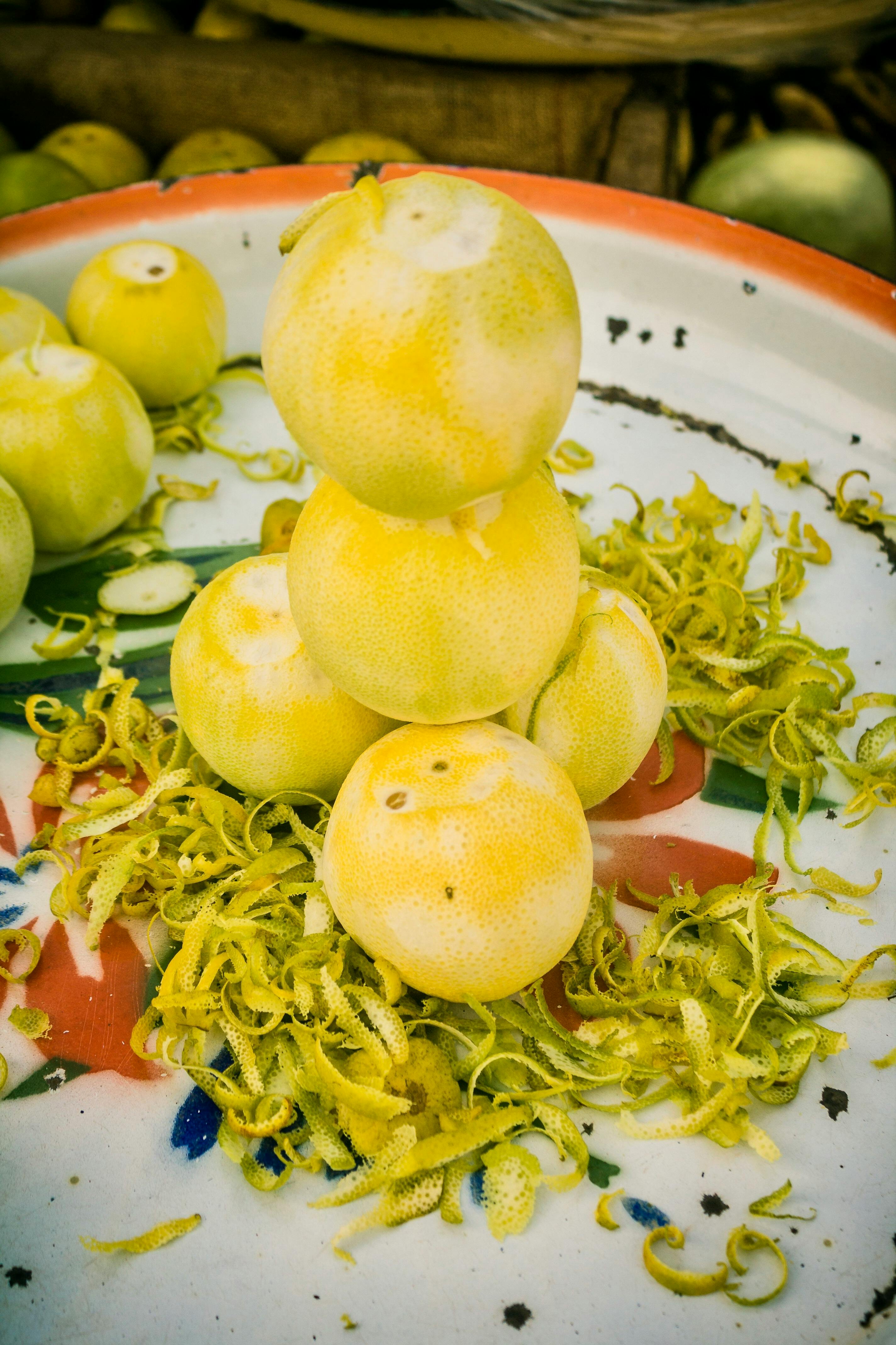 Stack of fresh lemons with zest on a vibrant plate, showcasing citrus freshness.