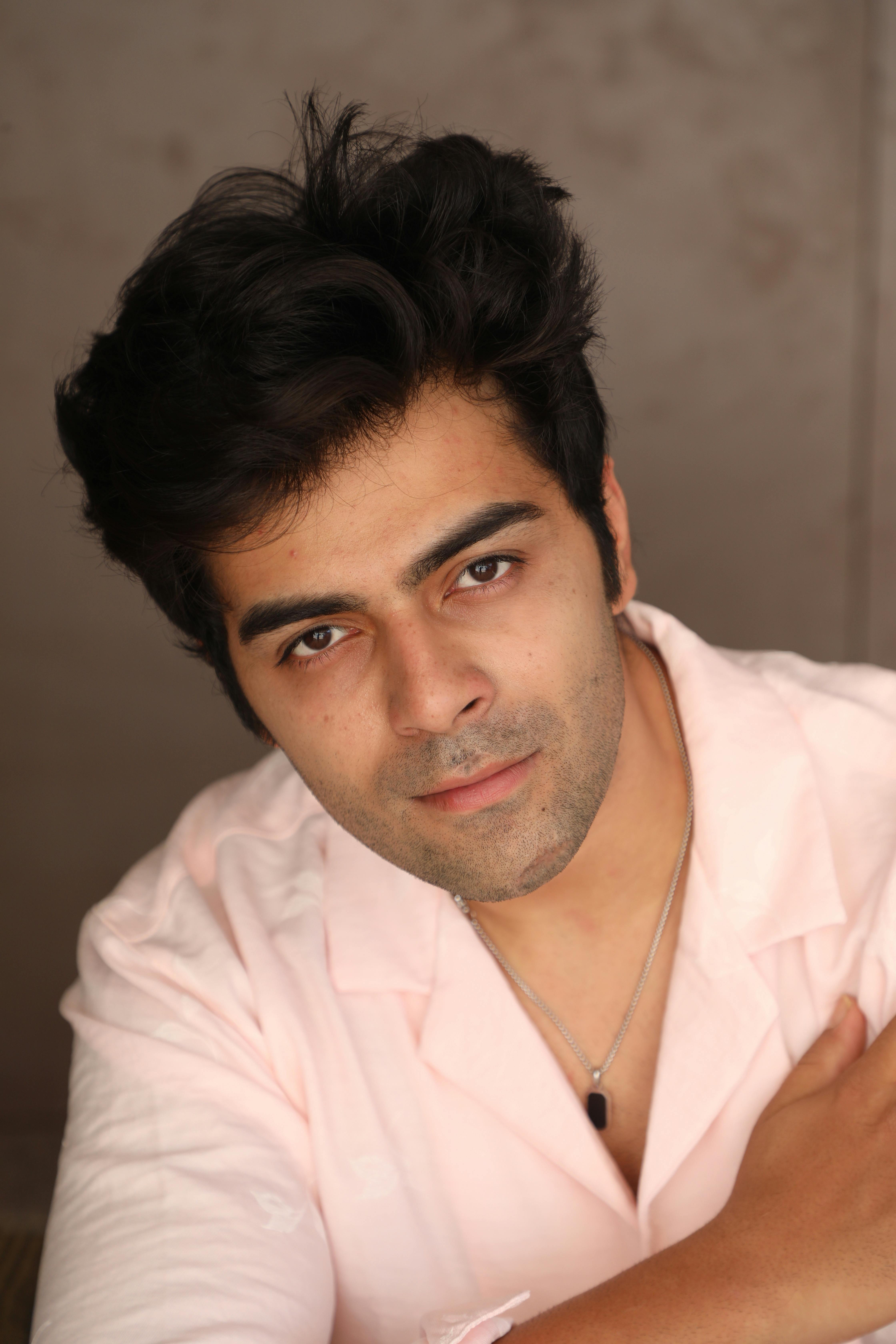 Close-up portrait of a man wearing a pink shirt with a calm expression.