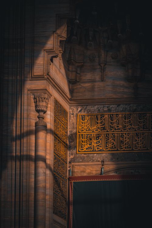 Free Intricate architectural details featuring Arabic calligraphy illuminated by dramatic light and shadow contrast. Stock Photo