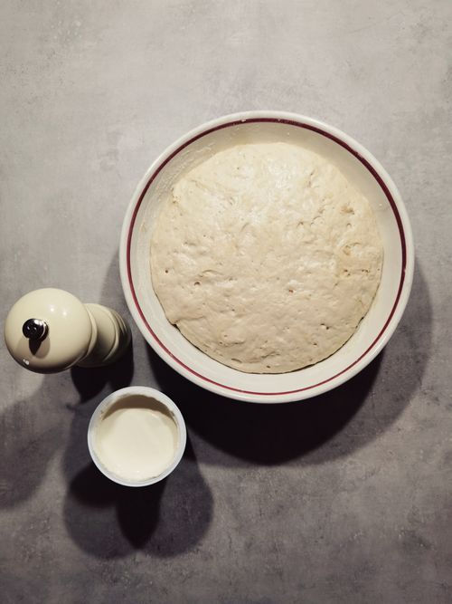 Free Top view of proofed bread dough with pepper grinder and cream on a kitchen counter. Stock Photo