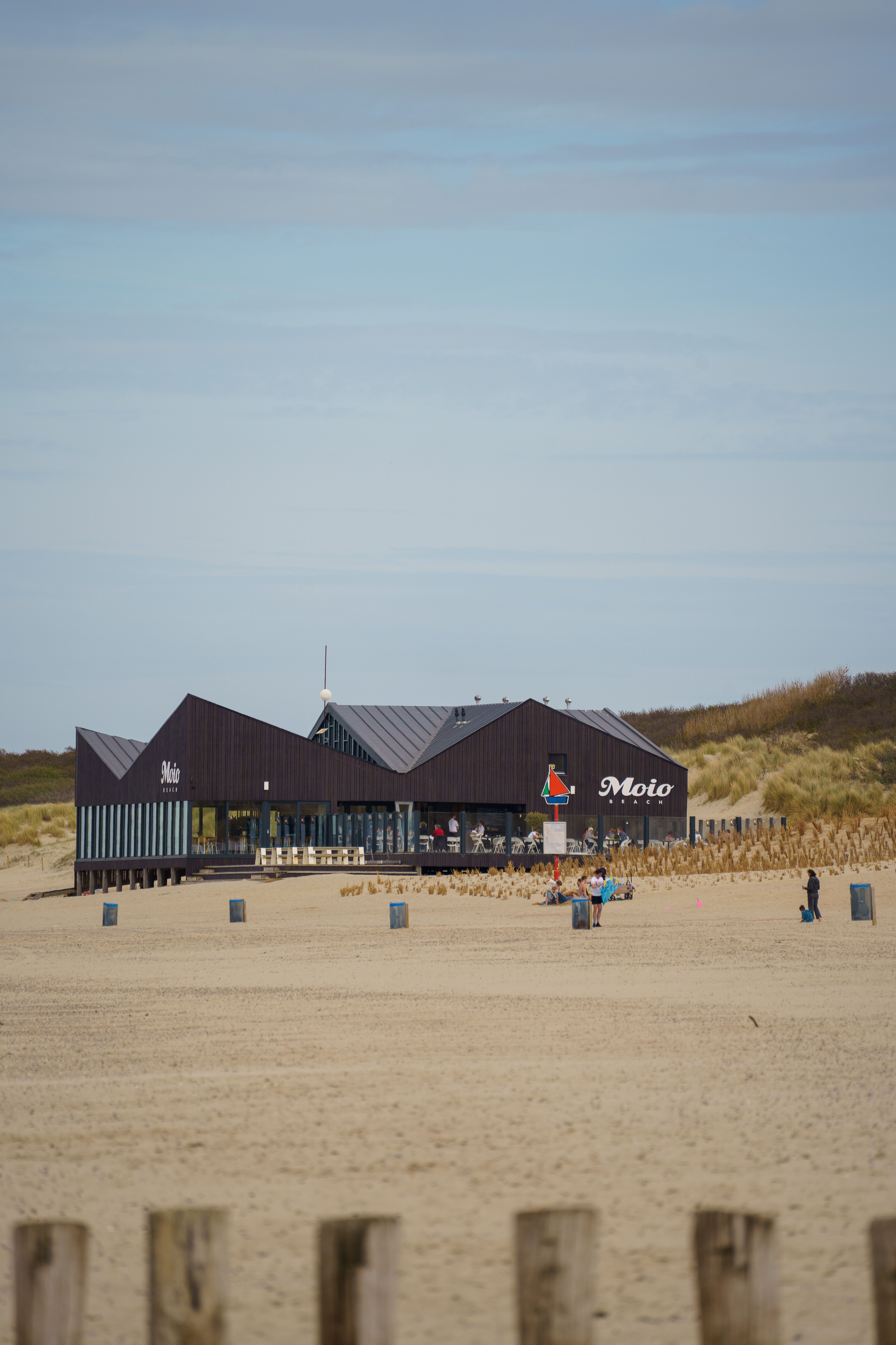 Modern beachside restaurant in Cadzand, Zeeland with few visitors and a sandy landscape.
