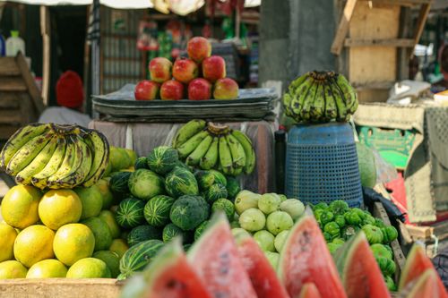 Free A colorful display of fresh fruits at an outdoor market showcasing bananas, apples, and more. Stock Photo