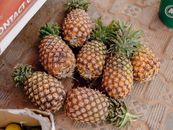 Cluster of ripe pineapples laid out on textured floor at Nigerian market.