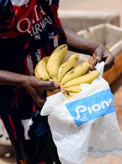 Free A man holds a bunch of fresh bananas in a plastic bag, captured outdoors in Jos, Nigeria. Stock Photo