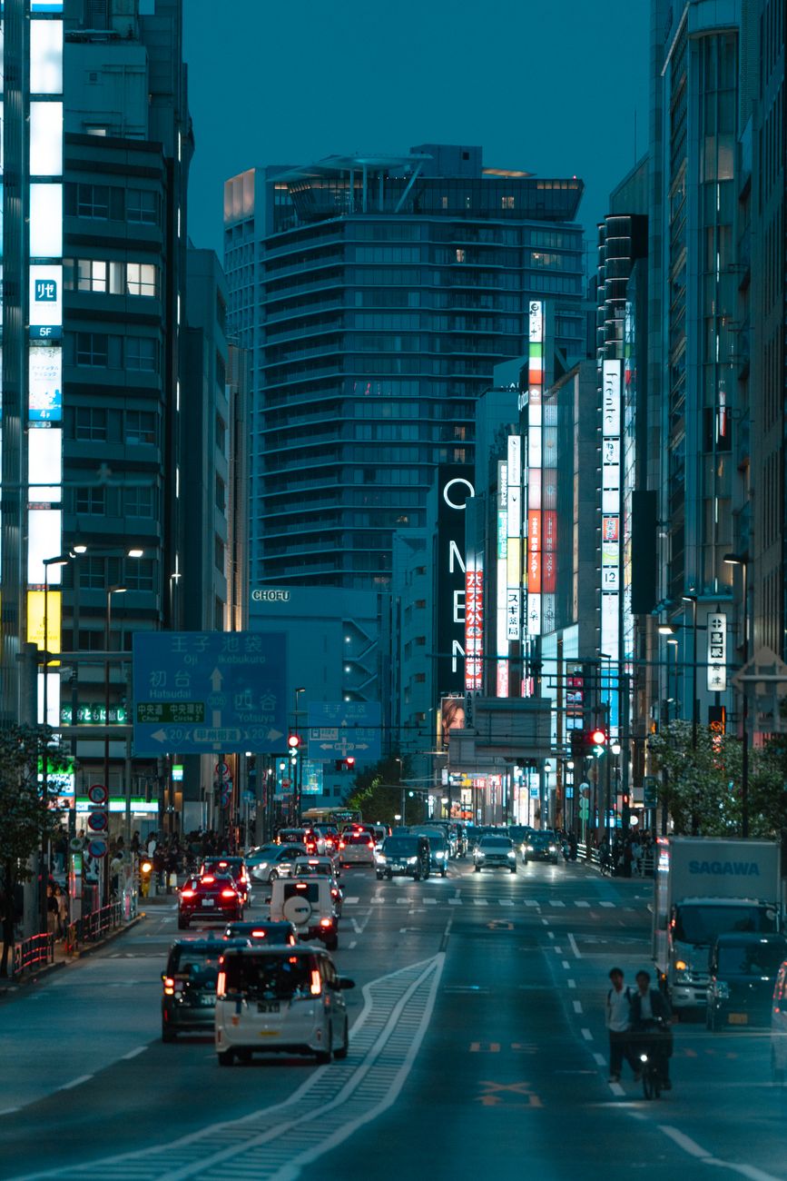 Tokyo city street bustling with traffic and vibrant neon lights during twilight.