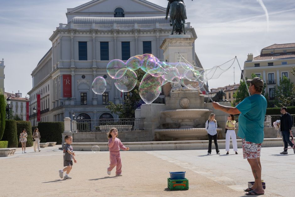 Joyful children playing with bubbles in front of Teatro Real, Madrid.