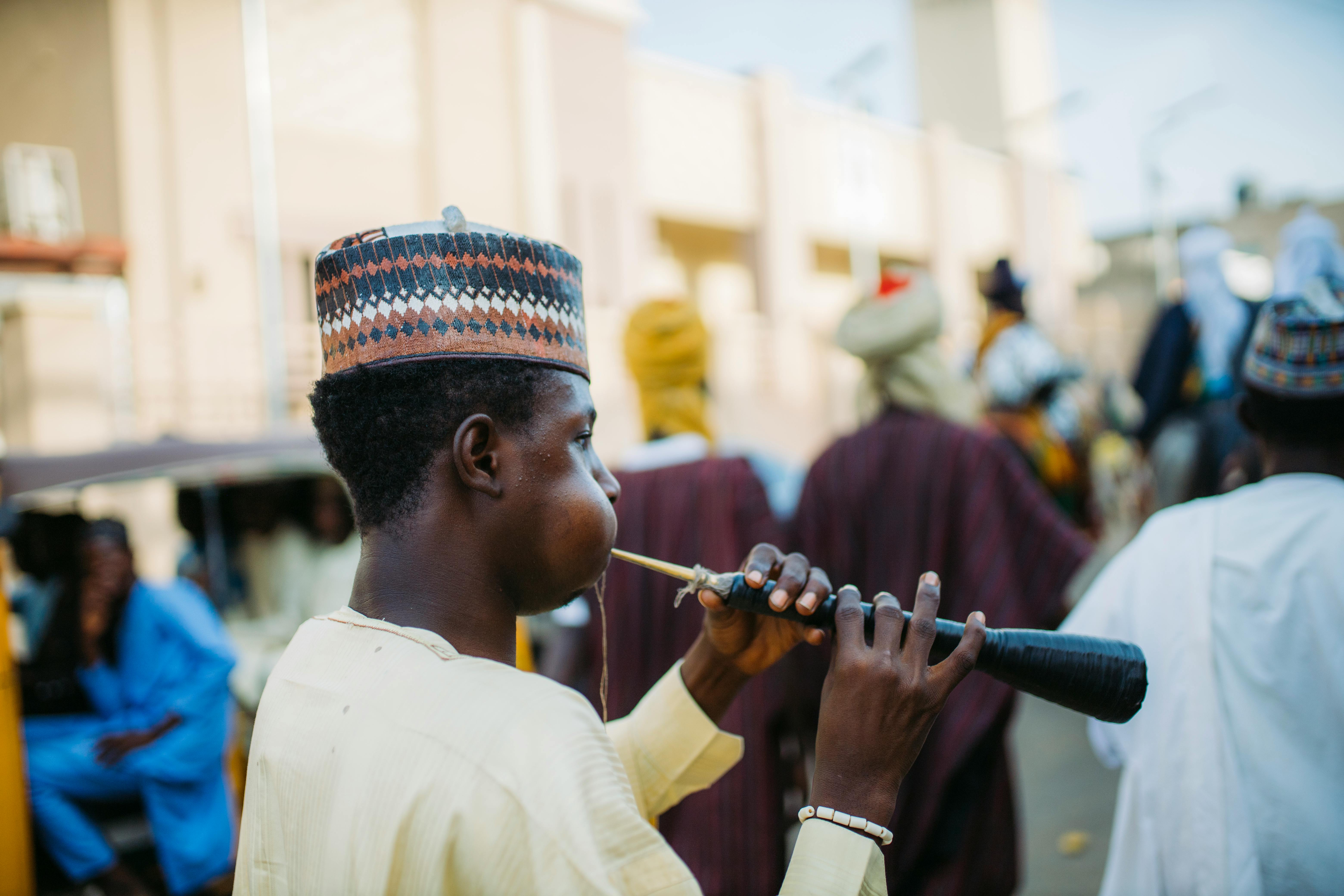 A musician in traditional attire playing an indigenous flute during a cultural festival.