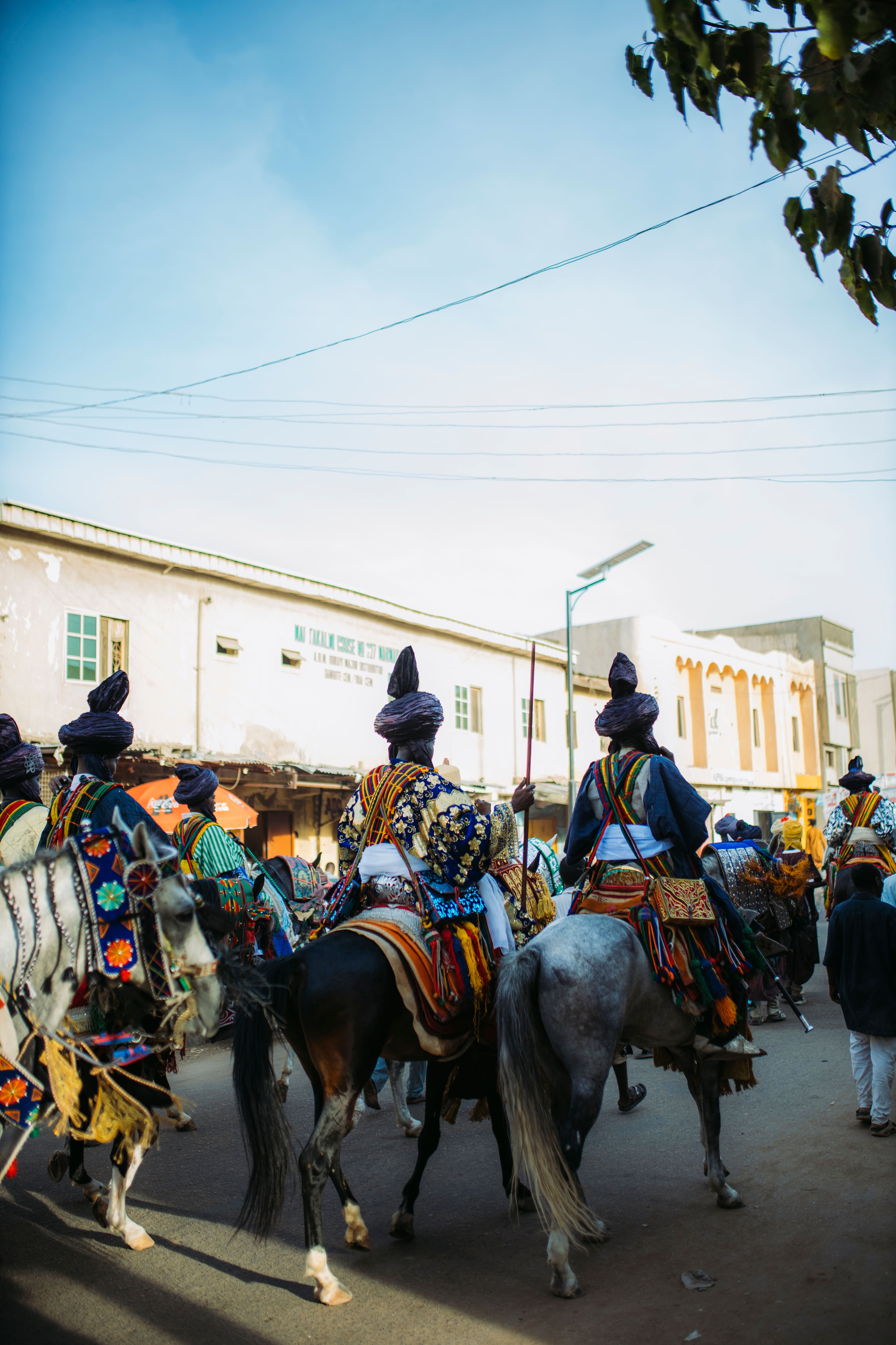 A vibrant parade featuring elaborately dressed riders on horseback, showcasing cultural attire outdoors.