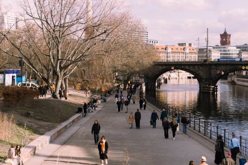 Free People strolling along a riverside path in spring with historic Berlin buildings in the background. Stock Photo