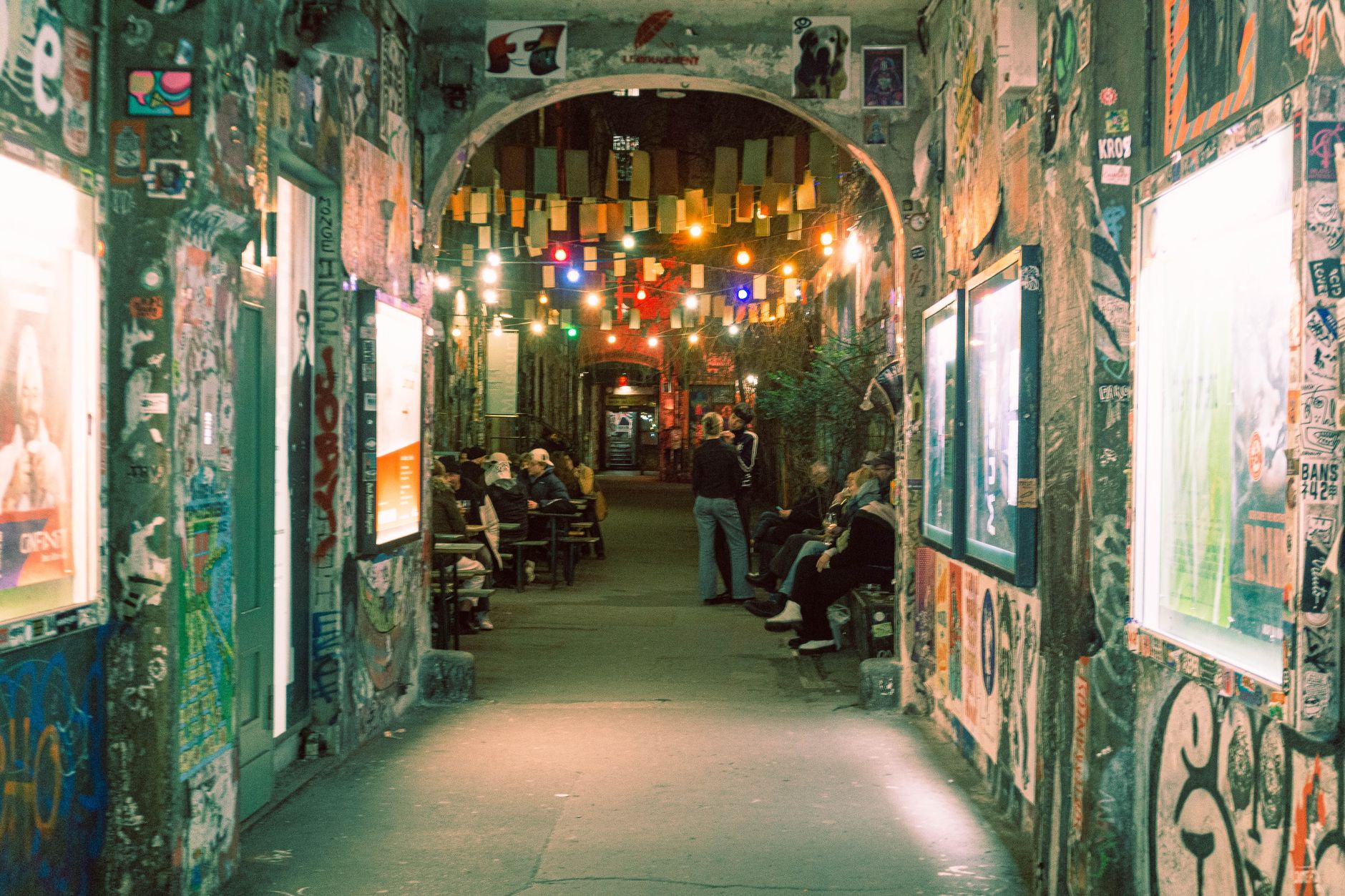 Explore a colorful Berlin alley filled with street art and vibrant lights, capturing urban culture at its finest.