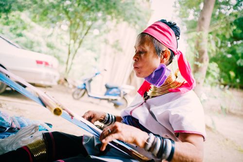 Free A Burmese woman in traditional attire weaves outdoors in Myanmar. Stock Photo