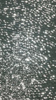 Captivating sunlight reflections on a rippling water surface create a magical, abstract pattern.