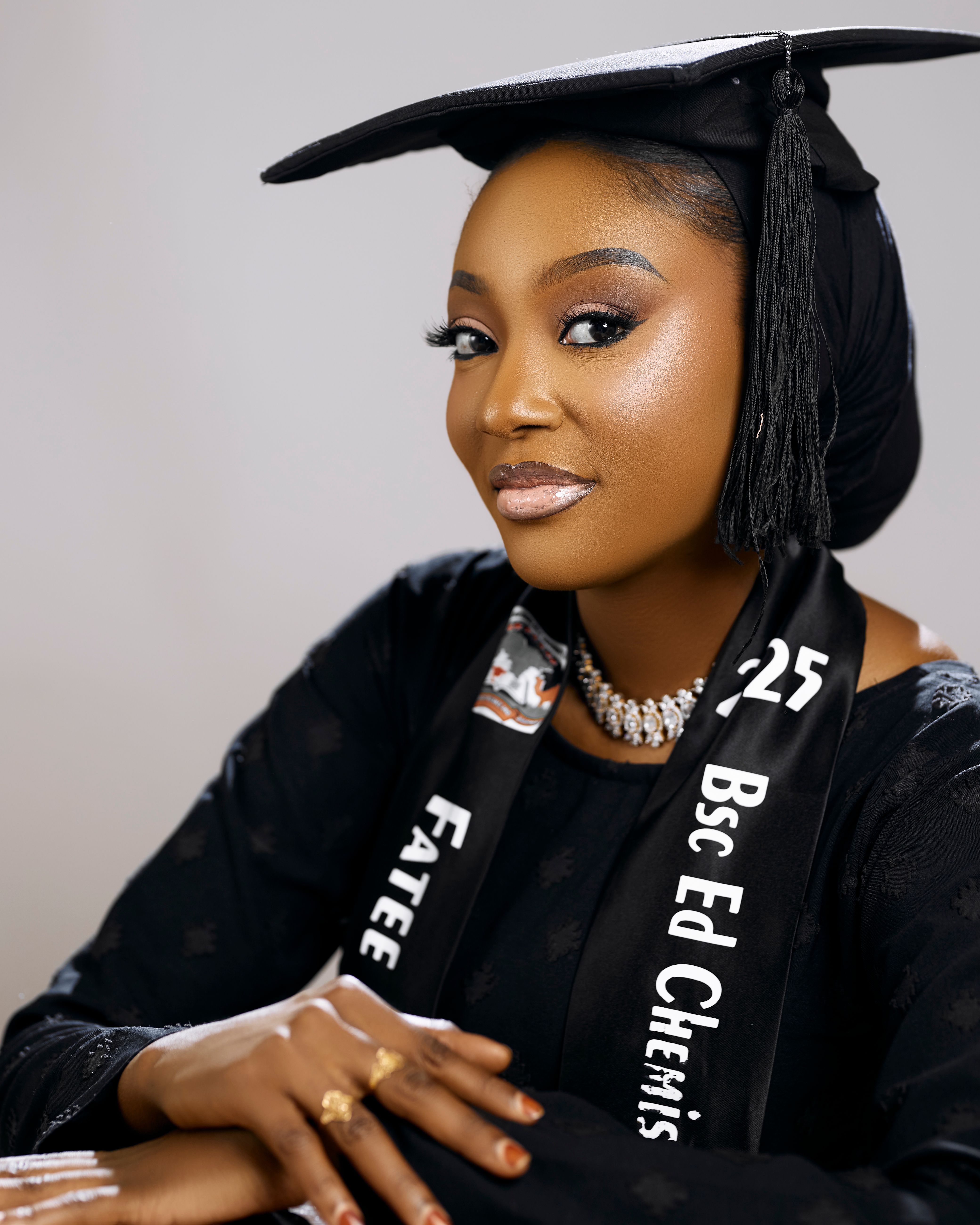 Stylish graduation portrait of a young woman in Kano, Nigeria, wearing a cap and gown with an attractive smile.