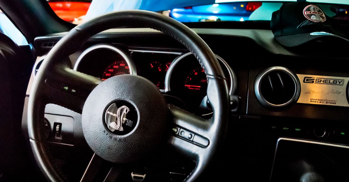Close-up of Shelby GT500 interior featuring steering wheel with cobra emblem and dashboard gauges.