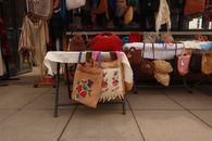 A variety of handcrafted bags showcased on an outdoor market stall, perfect for fashion enthusiasts.