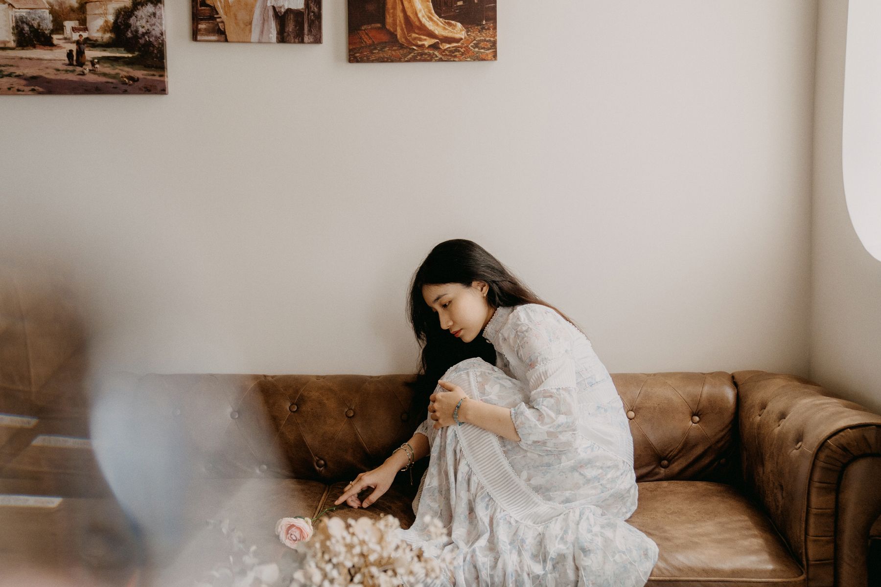 Woman seated on a vintage couch in a warm, daylit living room — photo by Huỳnh Như Mavi on Pexels
