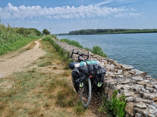 Kostnadsfria Cykel med cykelväskor på en lantlig stig nära floden i Pisa, Toscana. Stock foto