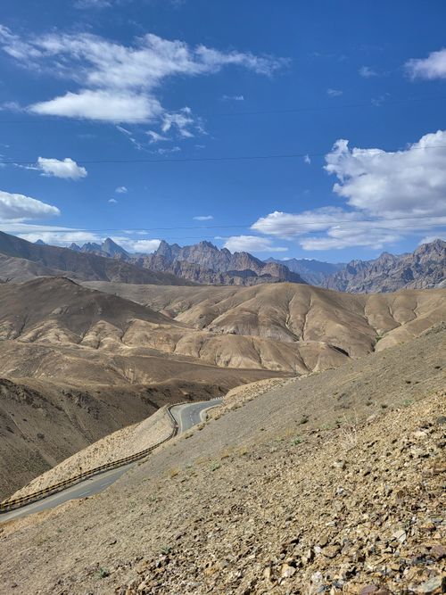 Free Mountainous landscape with a winding road under a vibrant blue sky. Stock Photo