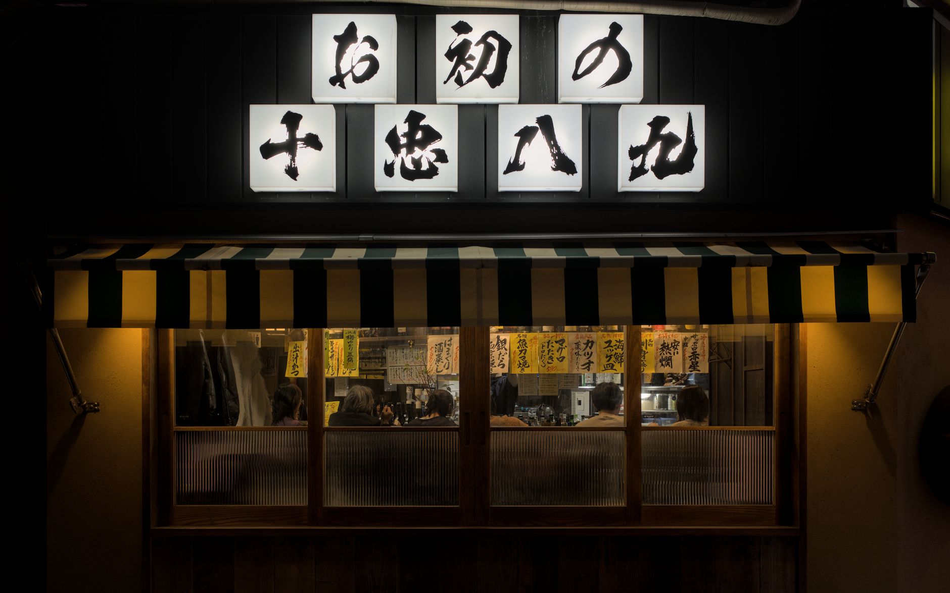 飲食店で食事をする客の表情をスタッフが観察しているシーン