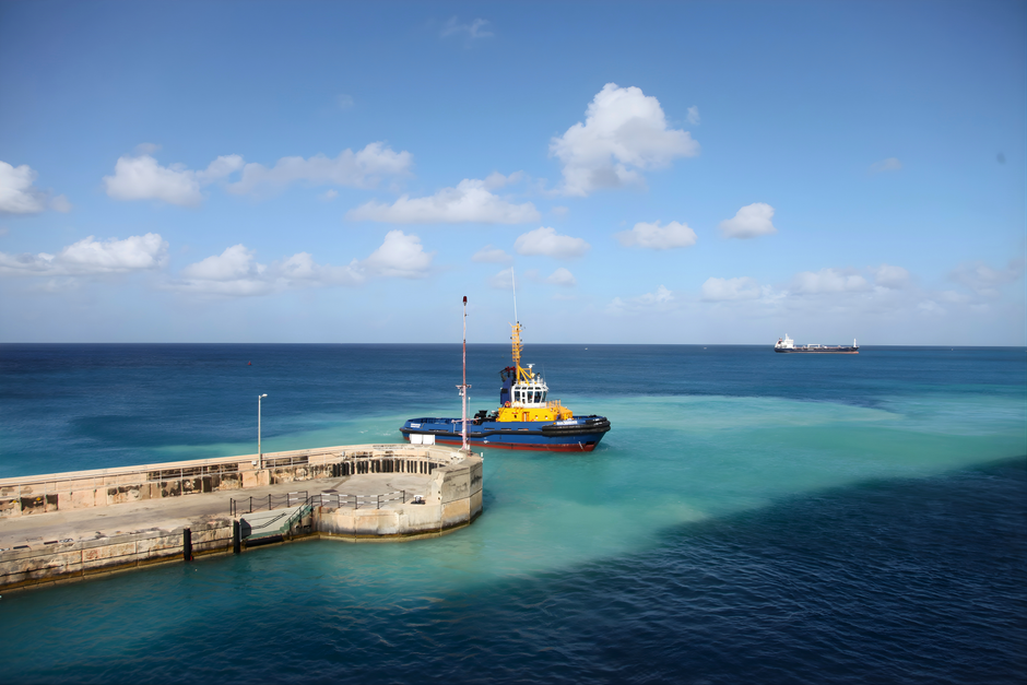 A vibrant tugboat by the dock in clear blue seas under a bright sky, ideal for travel themes.
