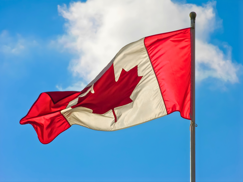 Free A vibrant Canadian flag waving against a blue sky with clouds. Stock Photo