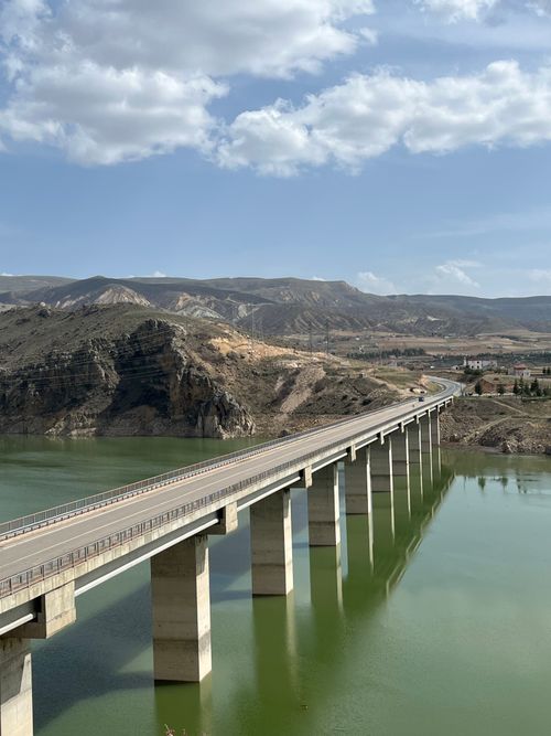 Free Bridge traversing a green river against a backdrop of rugged Turkish landscapes. Stock Photo