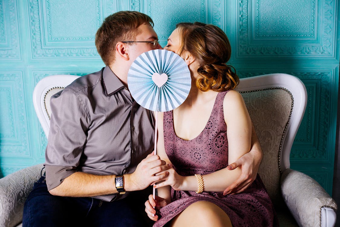 Free Woman and Man Sitting on Grey Suede Loveseat Stock Photo