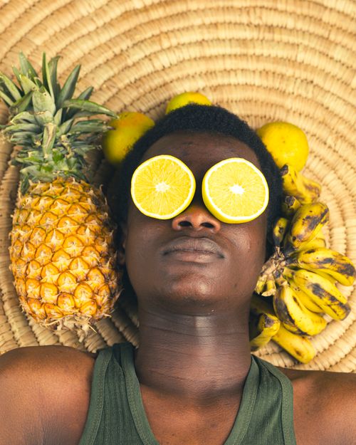 Free Creative portrait of a person with fruits like pineapple and banana, emphasizing African culture. Stock Photo