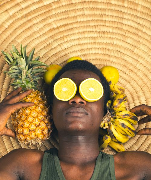 Free Person with fruit on a woven mat, embodying tropical vibes and relaxation. Stock Photo