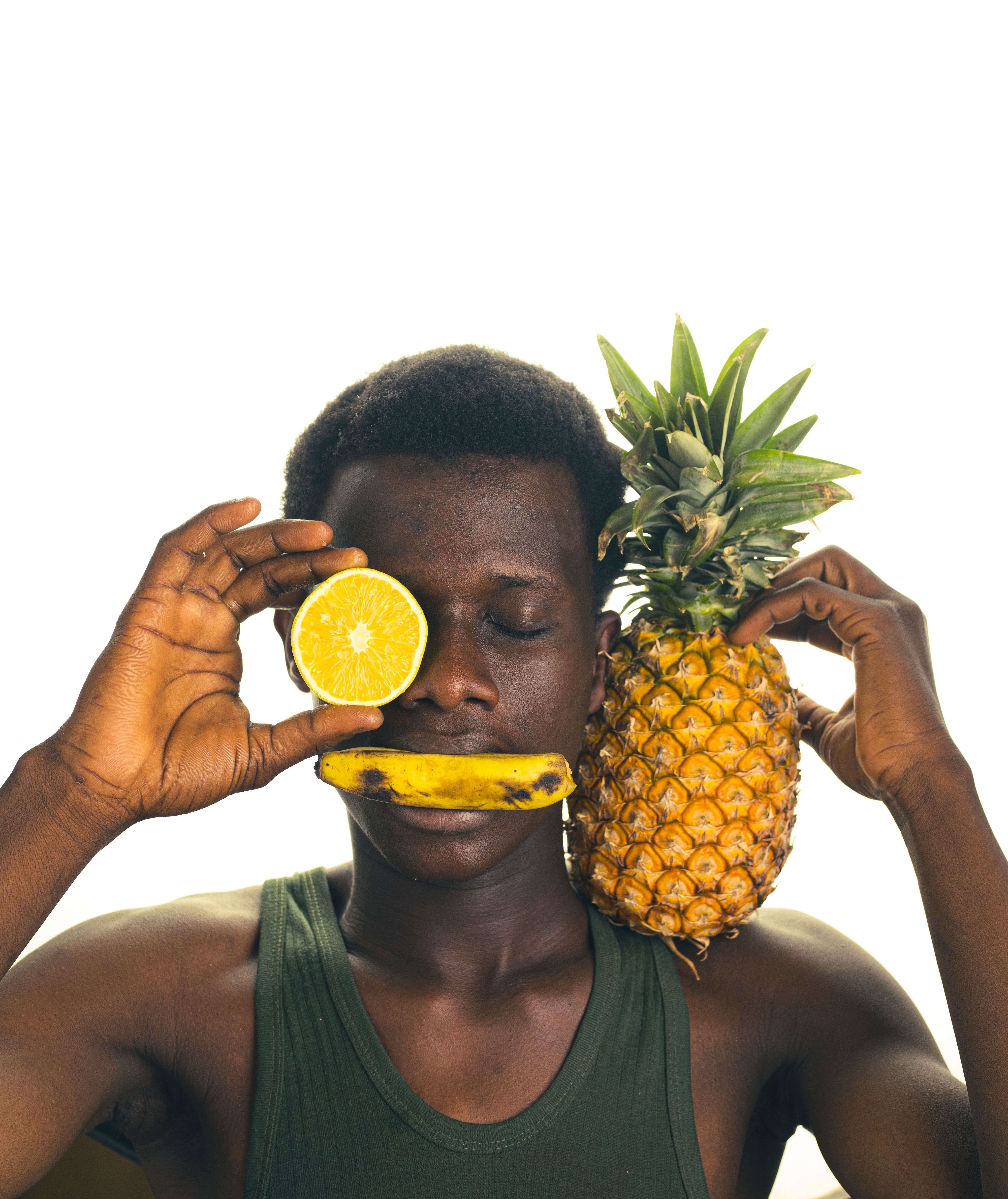 Creative portrait of a man with a pineapple, orange, and banana on a white background.
