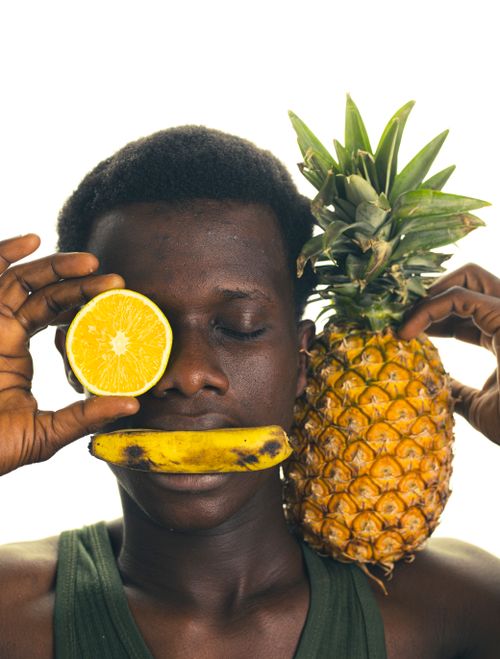 Free Artistic portrait featuring an African male with tropical fruits for a unique and vibrant look. Stock Photo