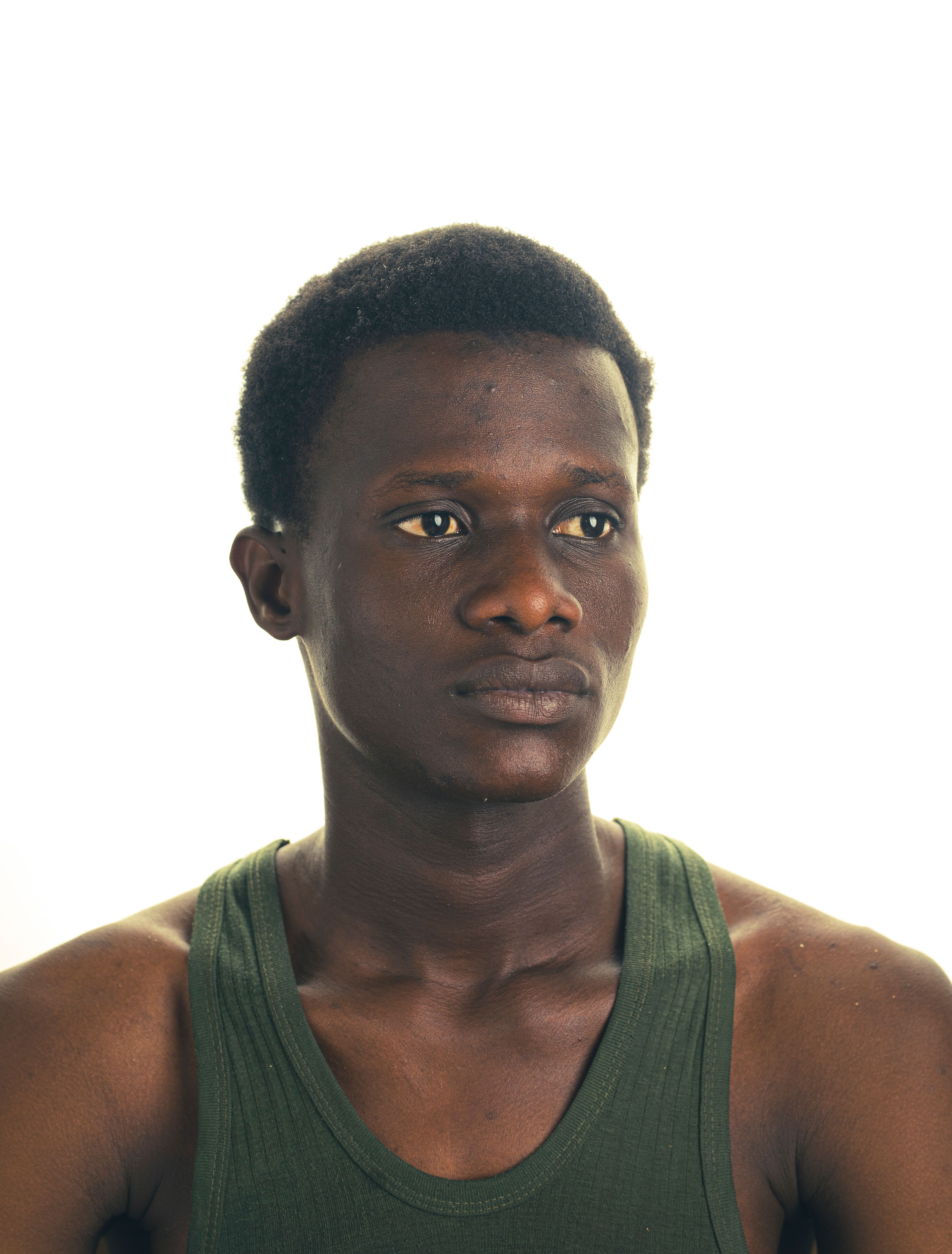 Studio portrait of a young man in Kano, Nigeria, with a neutral expression against a bright backdrop.