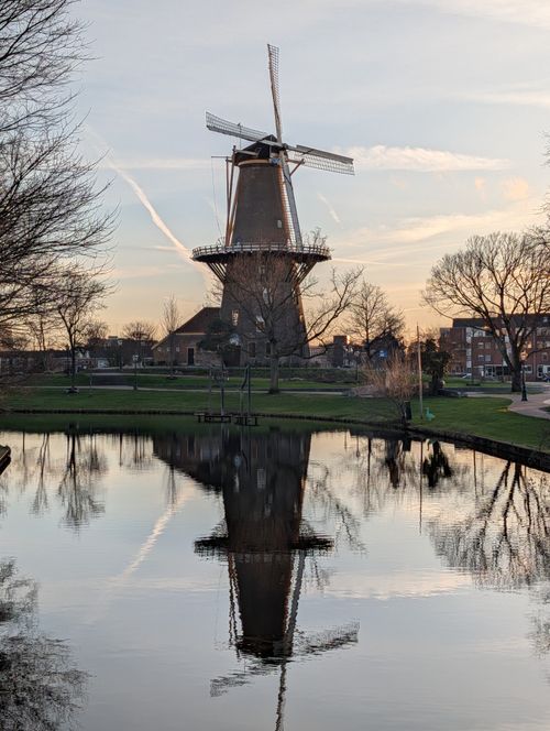 Free Picturesque windmill reflecting in a calm canal at sunset in Leiden, Netherlands. Stock Photo
