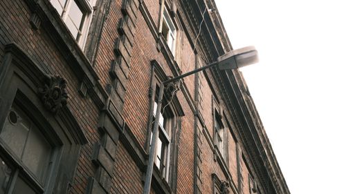 Free Angled view of a historic brick building facade with intricate window designs and a street light. Stock Photo