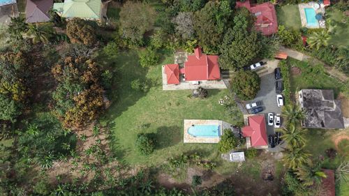 Free Bird's-eye view of a lush property with red-roofed buildings and swimming pools, surrounded by tropical greenery. Stock Photo