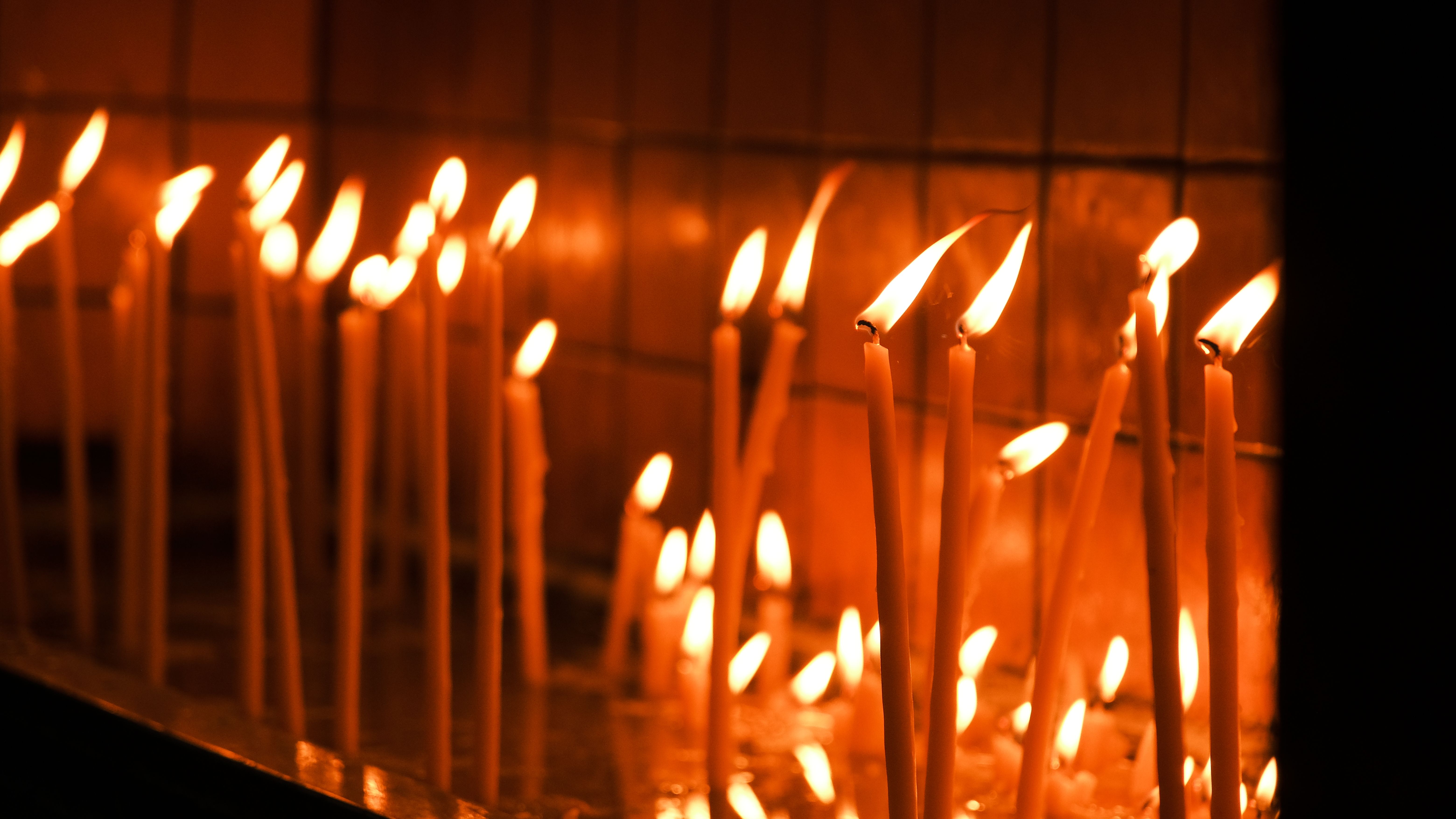 A serene image of tall candles glowing warmly in a dimly lit room, creating a peaceful ambience.