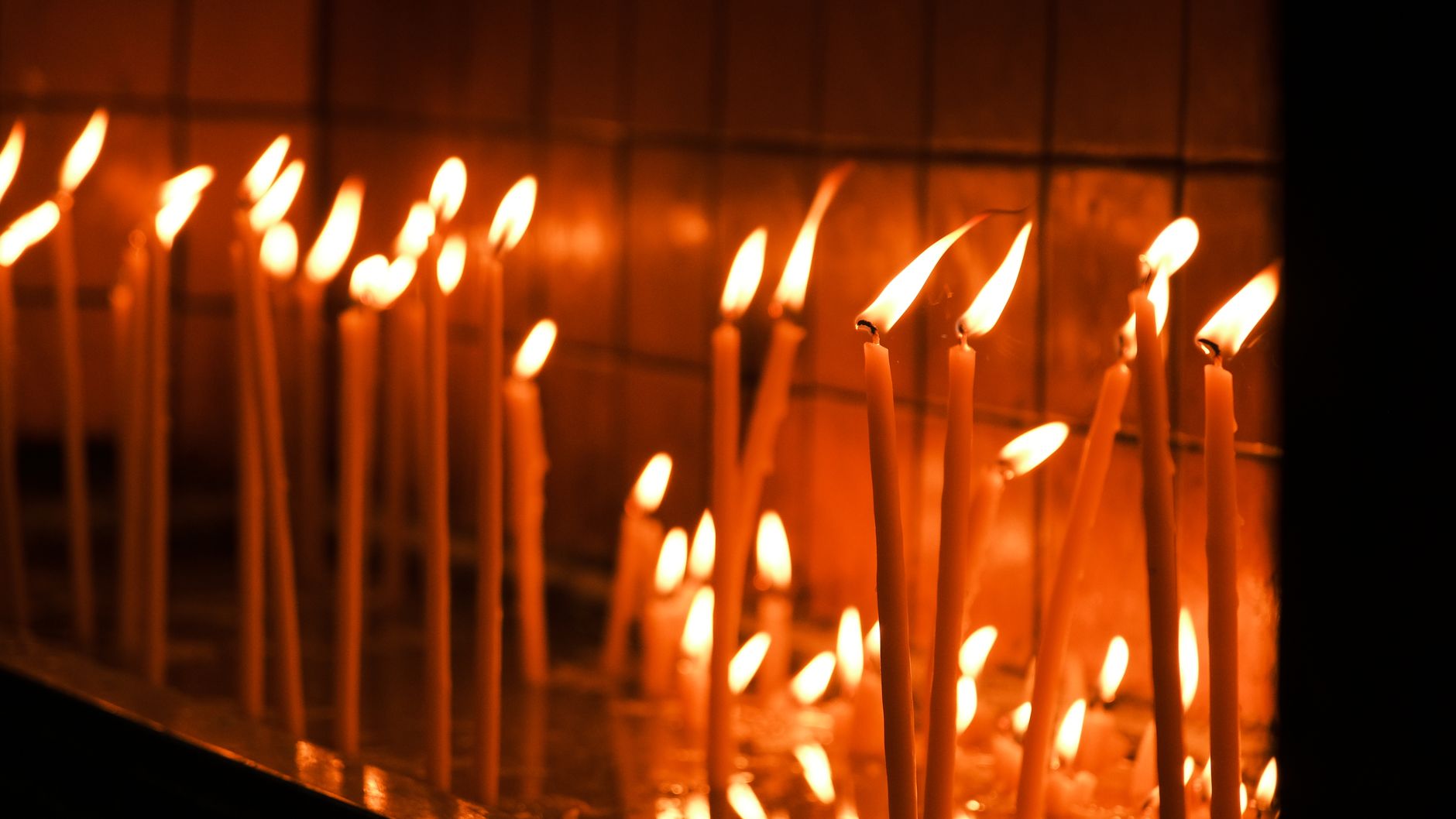 A serene image of tall candles glowing warmly in a dimly lit room, creating a peaceful ambience.
