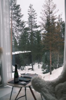Serene view of winter forest from a cozy cabin window with a table setting.