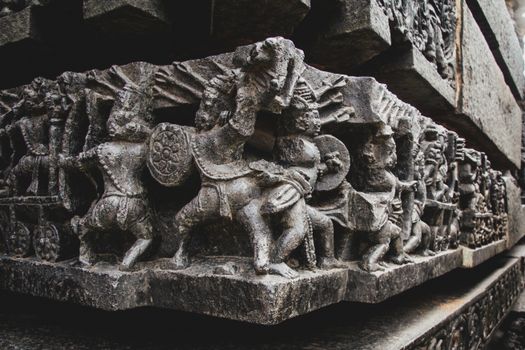 Detailed stone carvings depicting historical scenes on a temple wall, showcasing ancient artistry.