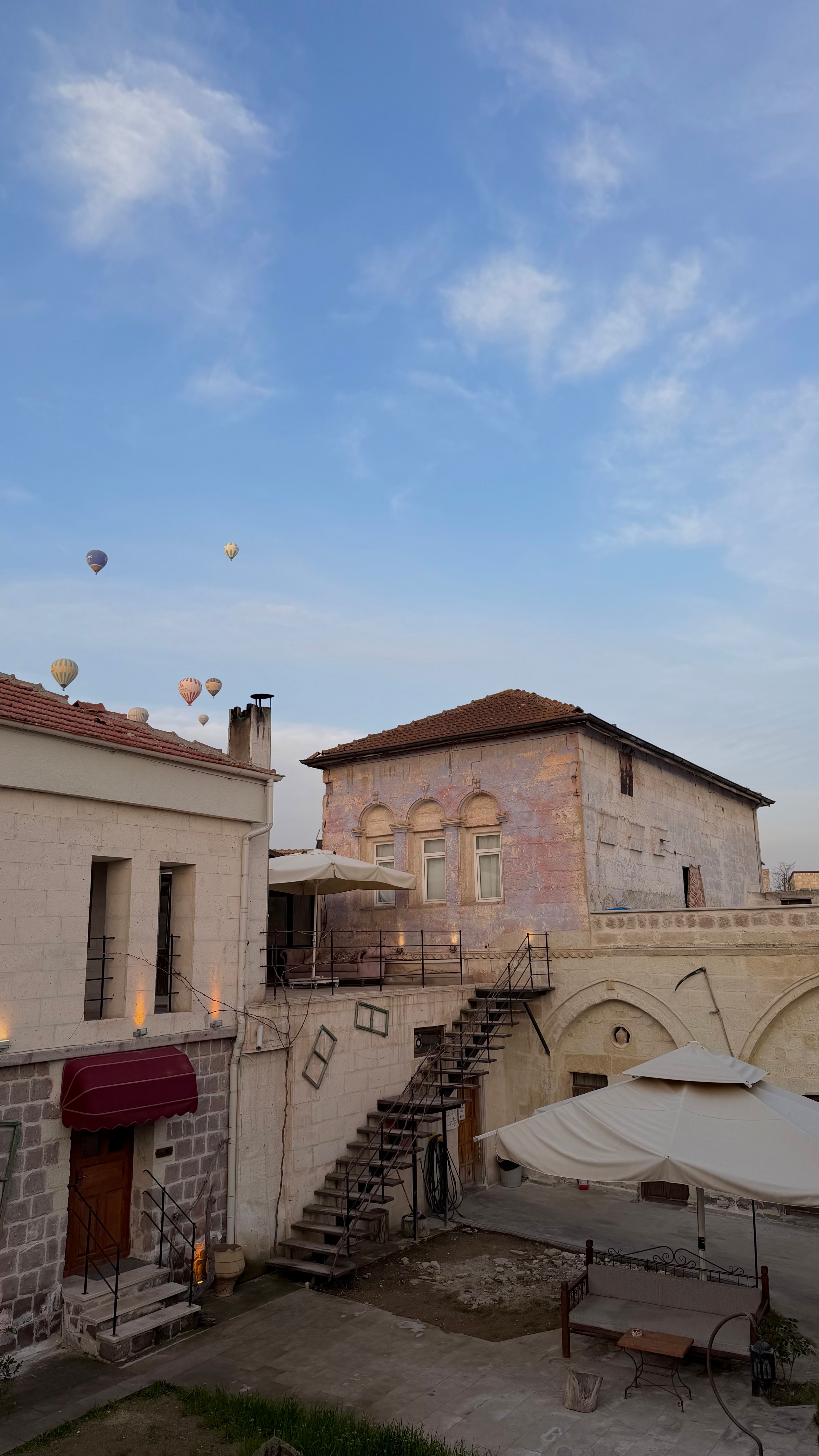 Scenic view of traditional Cappadocia buildings with hot air balloons in the sky, perfect for travel themes.