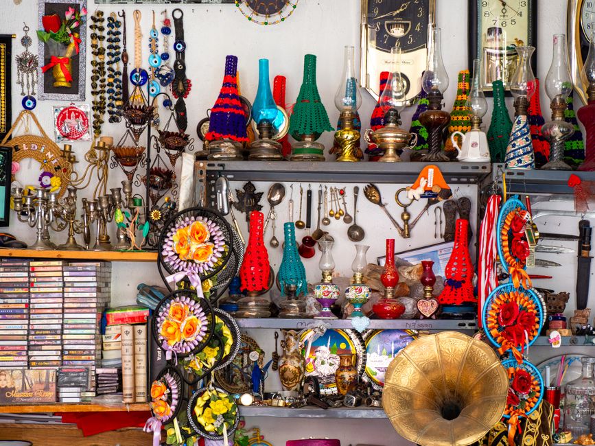 A vibrant display of vintage collectibles including lanterns, gramophone, and cultural artifacts on a shelf.