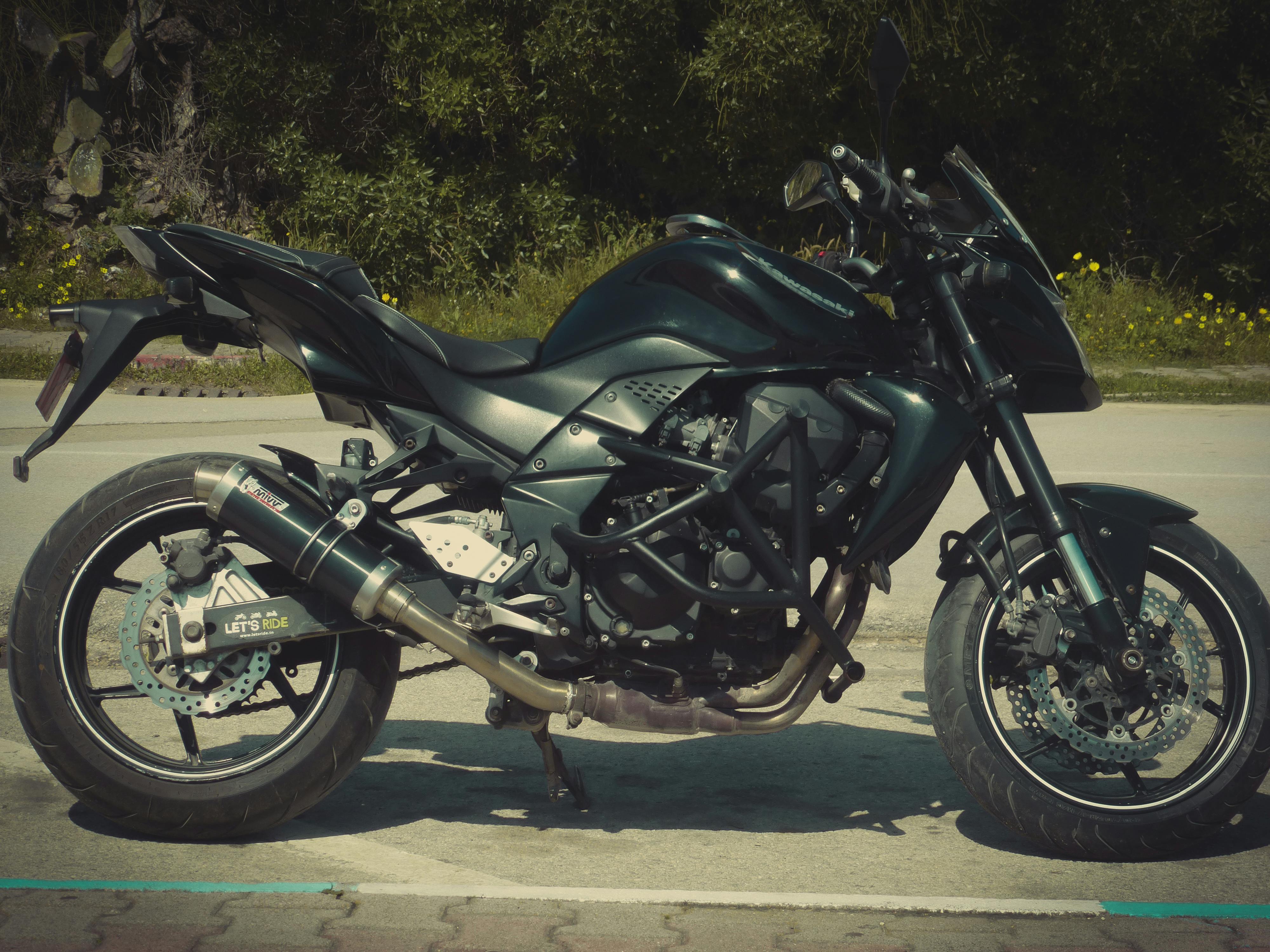 A sleek black sports motorcycle parked outdoors on a sunny day, ready for a ride.