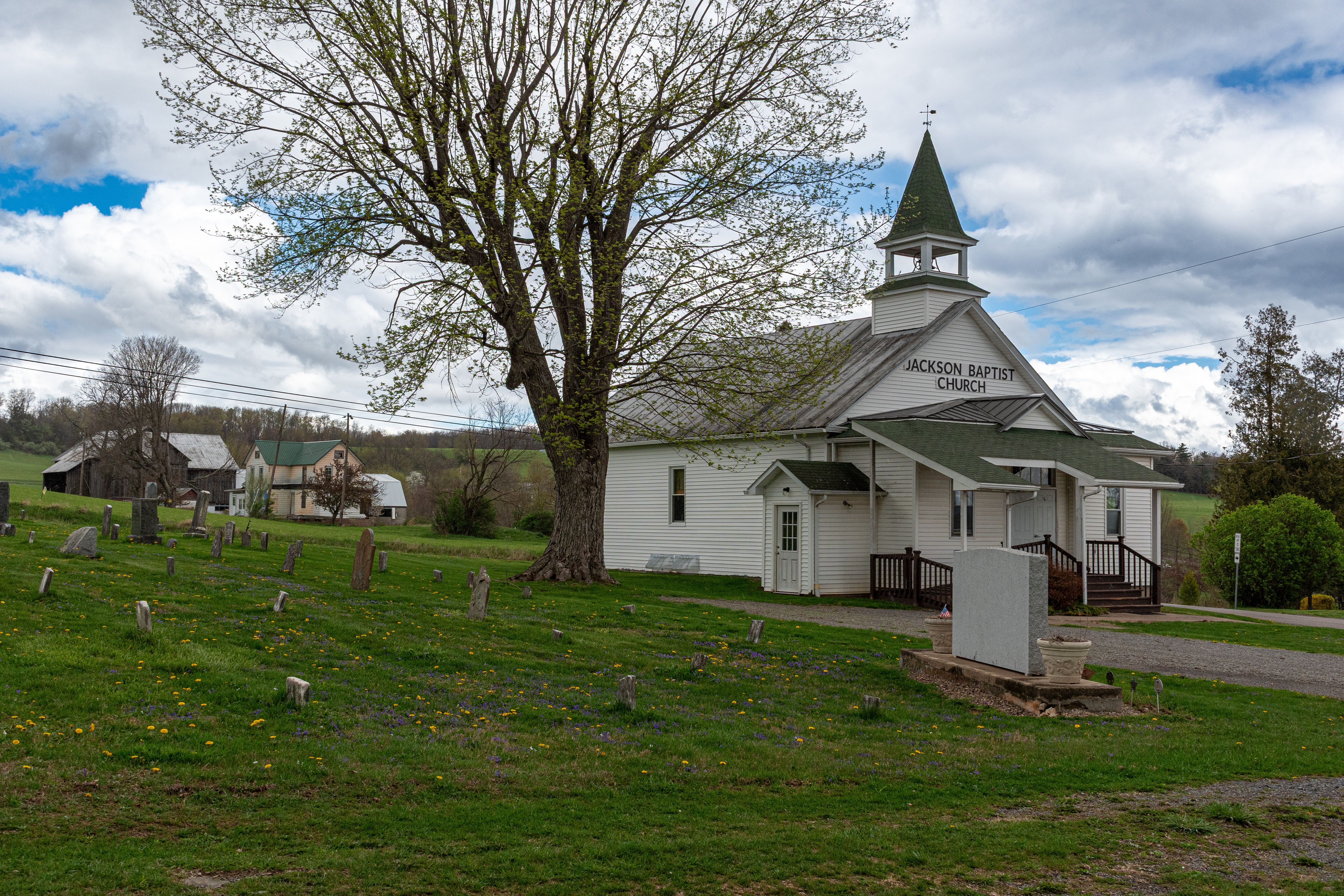 A scenic view of the historic Jackson Baptist Church and adjacent cemetery in a rural landscape.