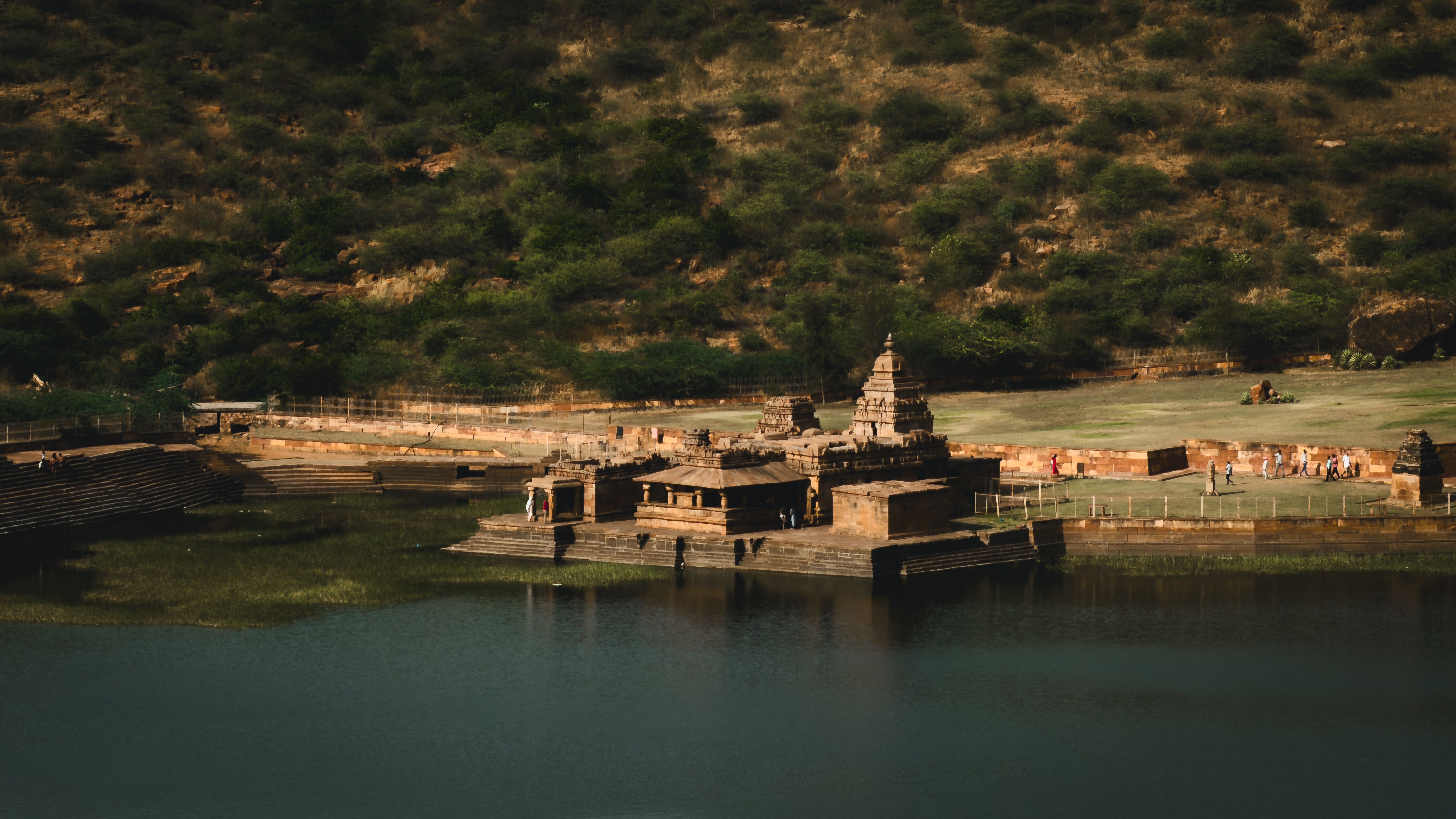 A stunning view of ancient temples by Agastya Lake in Badami, Karnataka, India, showcasing historic architecture.