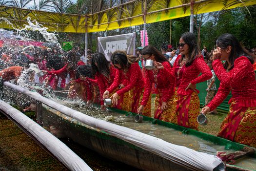 A vibrant water festival celebration with people in traditional attire participating in outdoor water activities.