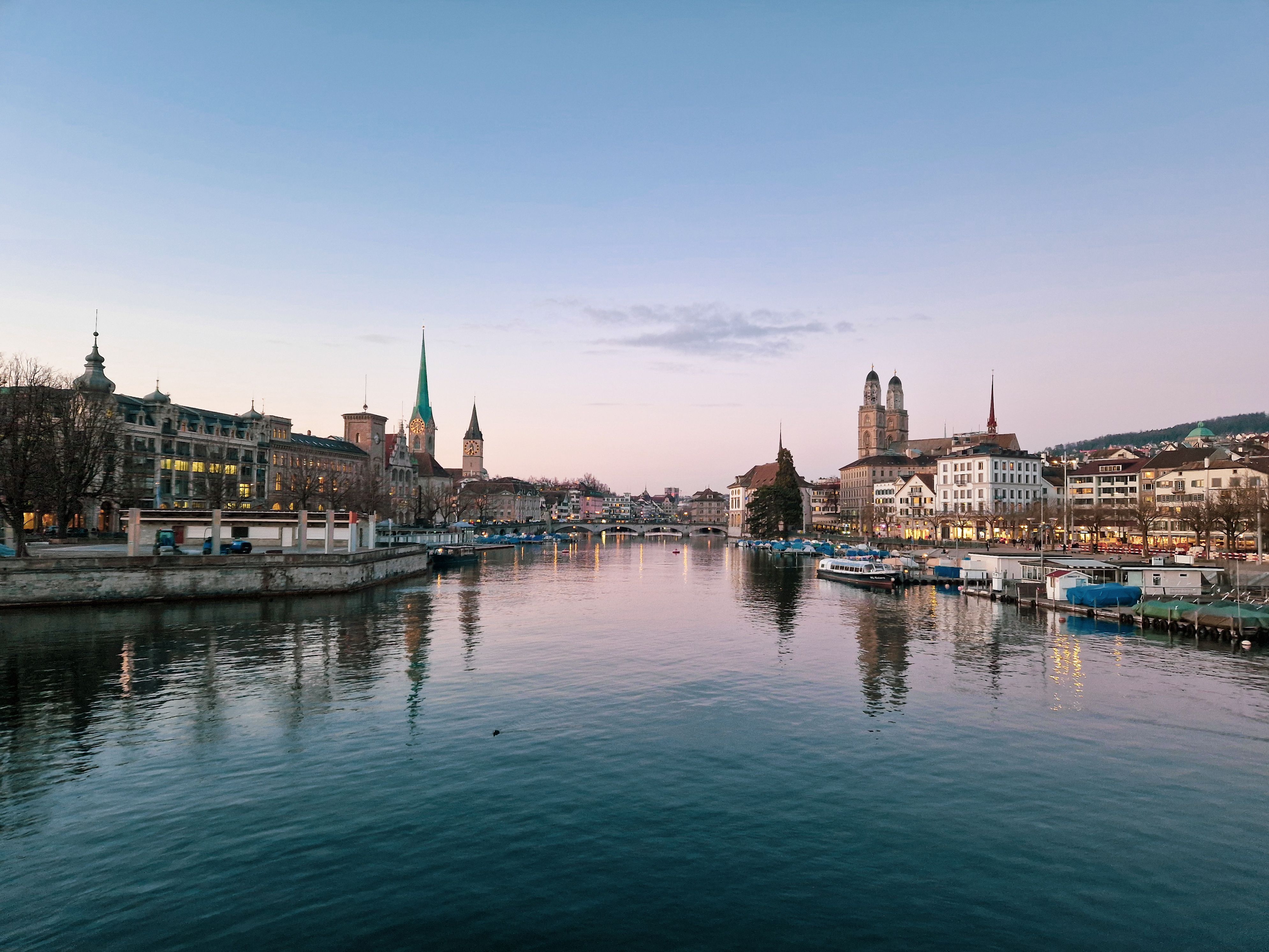 Zurich skyline at dusk along the Limmat River with illuminated historic buildings and Swiss city architecture