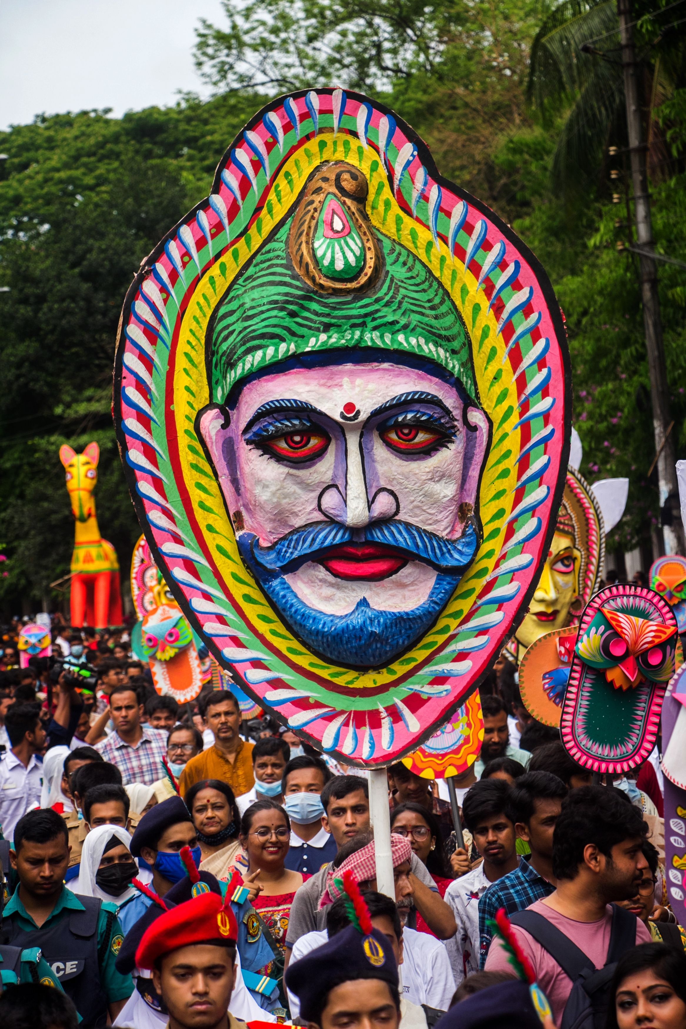 Colorful masks and vibrant crowd in a cultural festival parade outdoors.