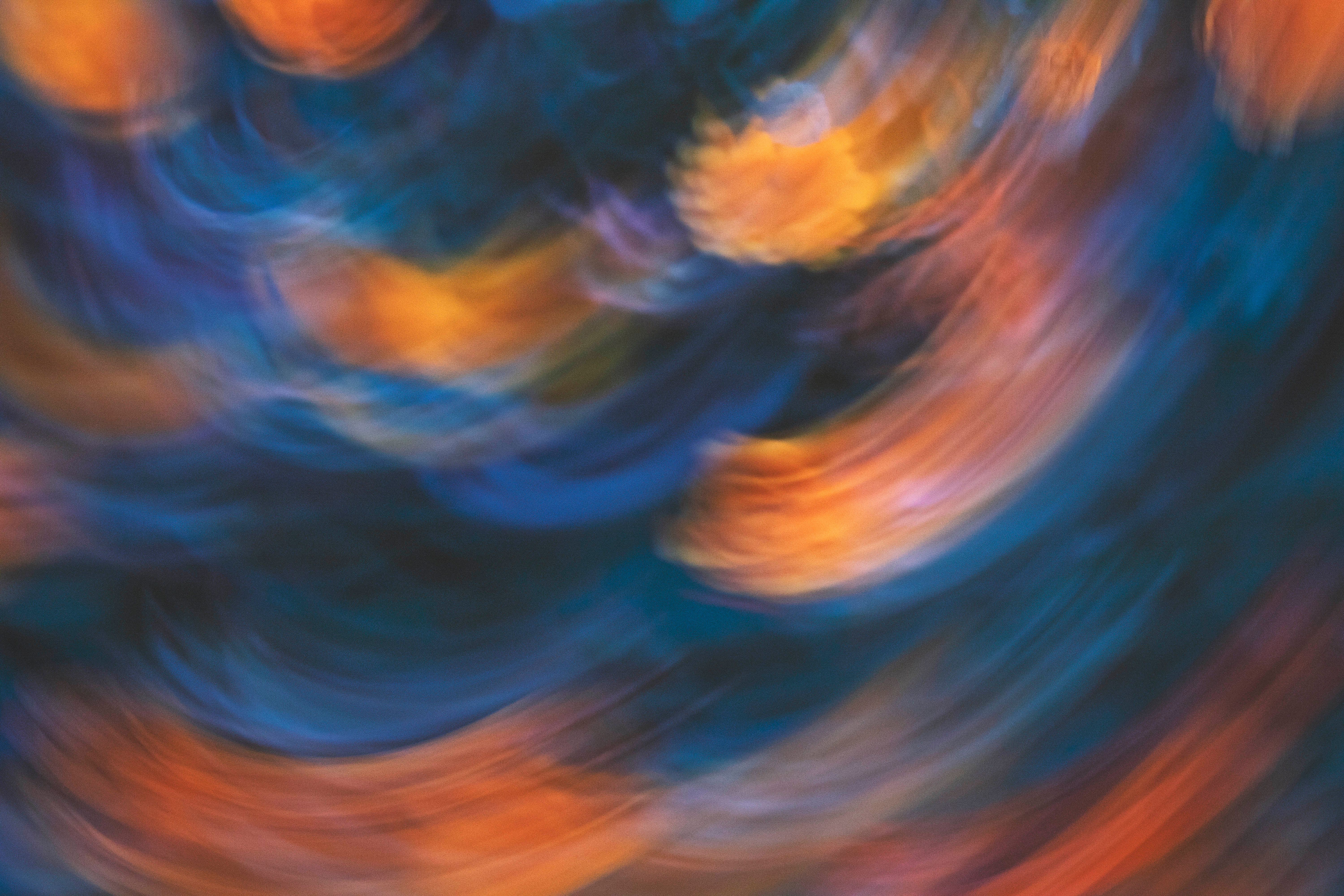 A vibrant abstract image of swirling light patterns in blue and orange hues.