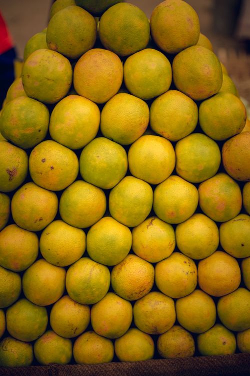 Free Close-up view of a pyramid stack of fresh oranges at a market stall. Stock Photo
